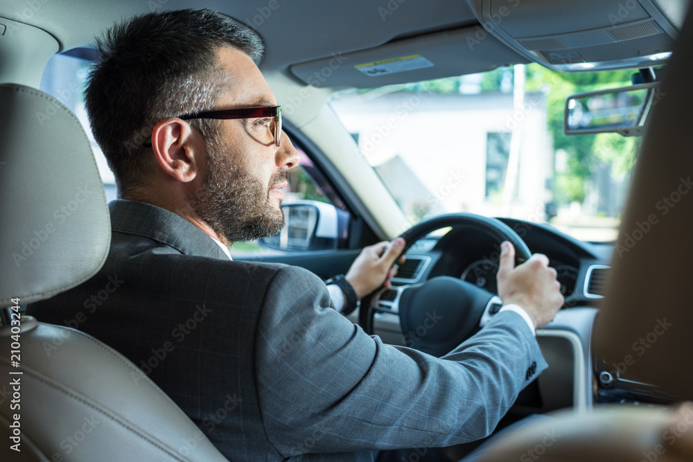 back view of businessman in suit and eyeglasses driving car alone back view of businessman in suit and eyeglasses driving car alone