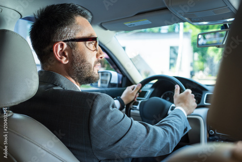 back view of businessman in suit and eyeglasses driving car alone © LIGHTFIELD STUDIOS