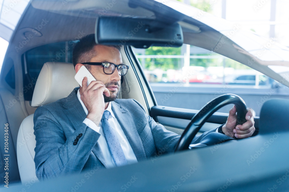 side view of businessman talking on smartphone while driving car side view of businessman talking on smartphone while driving car
