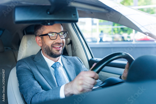 portrait of smiling businessman in suit and eyeglasses driving car alone © LIGHTFIELD STUDIOS