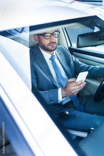 portrait of businessman with smartphone driving car © LIGHTFIELD STUDIOS