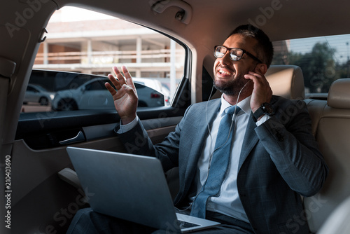 businessman in earphones with laptop listening music in car © LIGHTFIELD STUDIOS