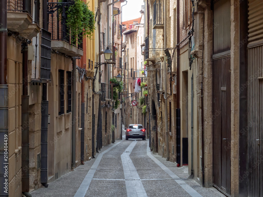 Fototapeta premium Car in a narrow cobblestone alley - Viana, Navarre, Spain