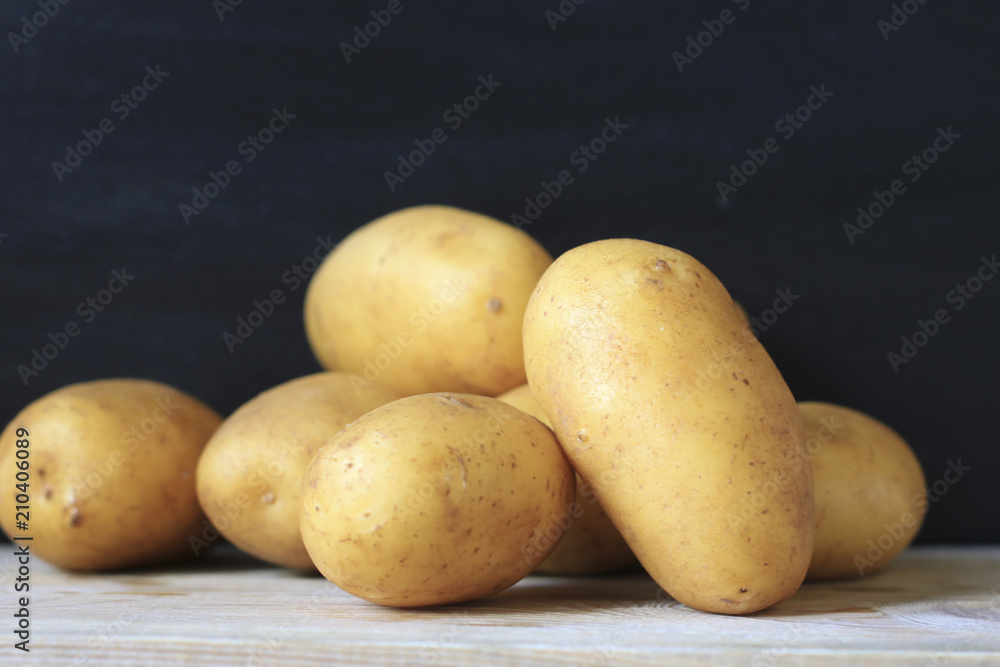 Raw young potatoes in a peel on a black background Raw young potatoes in a peel on a black background