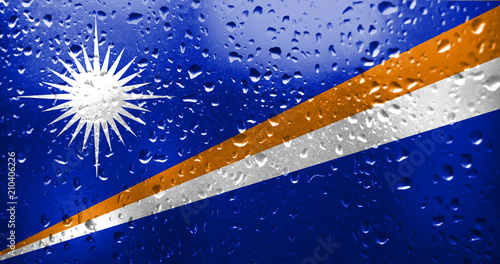Texture of the Marshall Islands flag on the glass with drops of rain.