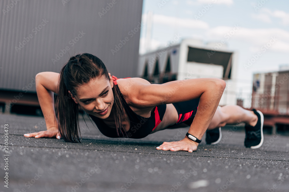 young smiling sportswoman doing push up on asphalt in city young smiling sportswoman doing push up on asphalt in city