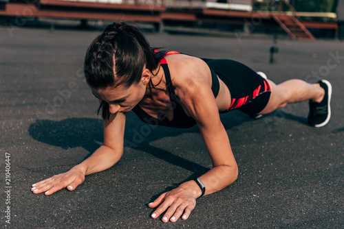 athletic woman doing plank on asphalt in city