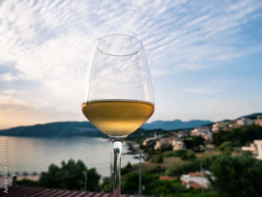 a glass of white wine with seascape at sunset