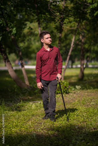 Young man standing, leaning on his cane