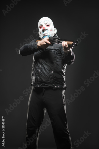 Fotografie, Obraz robber in the mask clown stands with a gun in his hands