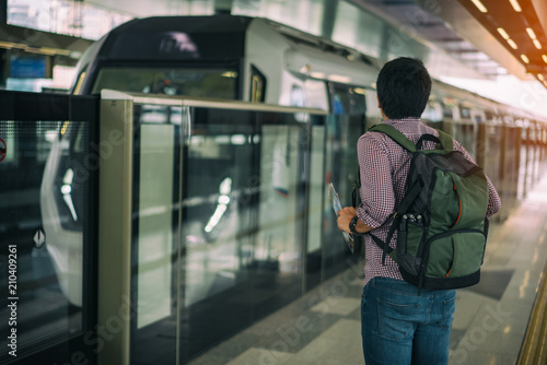 Canvas Print Young asian traveler waiting Mass Rapid Transit (MRT) train with background of cityscape in Kuala Lumpur