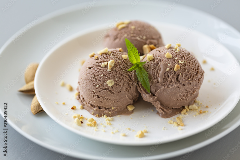 Tasty homemade bowl of chocolate ice cream with mint and nuts on a light background. Tasty homemade bowl of chocolate ice cream with mint and nuts on a light background.