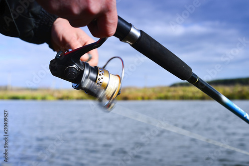 A fisherman catches a fish. Spinning reel closeup. Shallow depth of field on the spool of fishing line