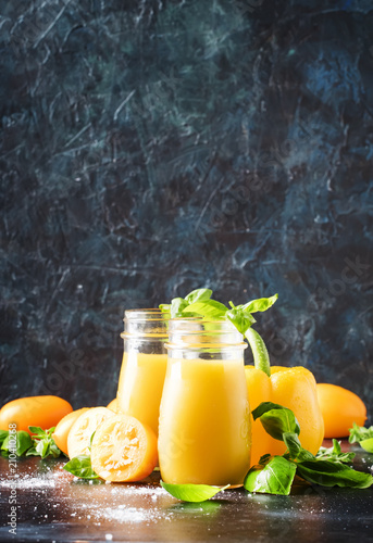 Healthy juice from yellow tomatoes and bell peppers with basil leaves in glass bottles, selective focus