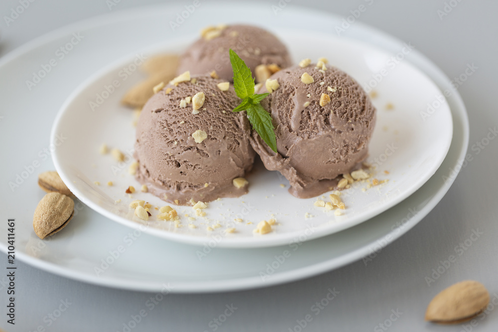 Tasty homemade bowl of chocolate ice cream with mint and nuts on a light background. Tasty homemade bowl of chocolate ice cream with mint and nuts on a light background.