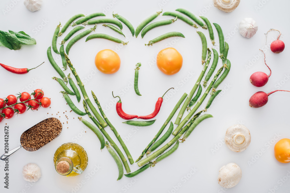 top view of heart made of fresh green peas and asparagus and smiley face from tomatoes and chili peppers isolated on white top view of heart made of fresh green peas and asparagus and smiley face from tomatoes and chili peppers isolated on white