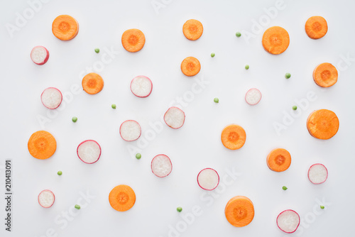 top view of fresh sliced carrot, radish and green peas isolated on white background
