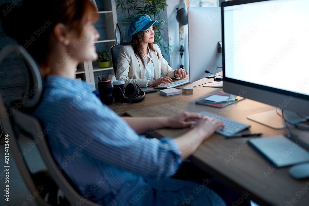 Obraz premium Modern woman designer smiling and working overtime at workplace.