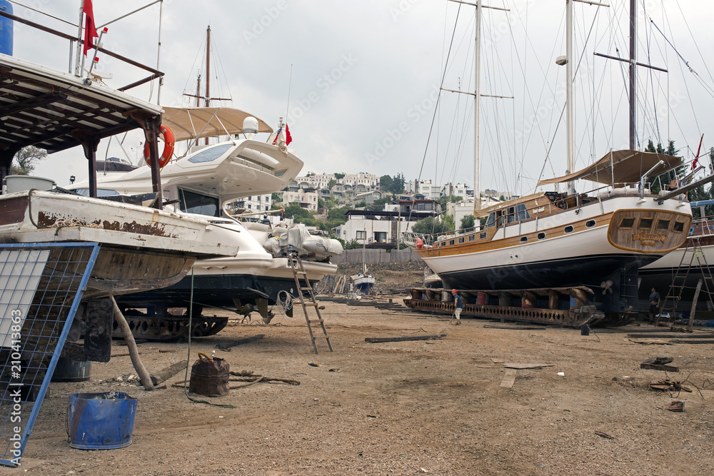 Fototapeta premium Fishing boats, wooden boats and ships on the lift in a shipyard in Bodrum, Turkey