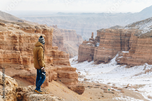 A cheerful traveler with a camera stands on the edge of the cliff in the Charyn canyon in Kazakhstan. Analogue of the American Grand Canyon.