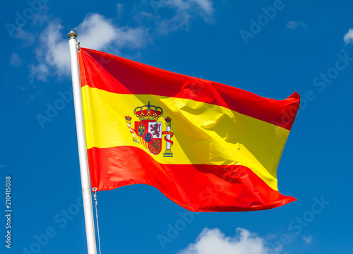 Canvas-taulu Flag of Spain waving in the wind on flagpole against the sky with clouds on sunn