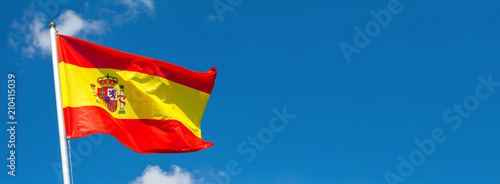 Obraz na płótnie Flag of Spain waving in the wind on flagpole against the sky with clouds on sunny day, banner, close-up w salonie