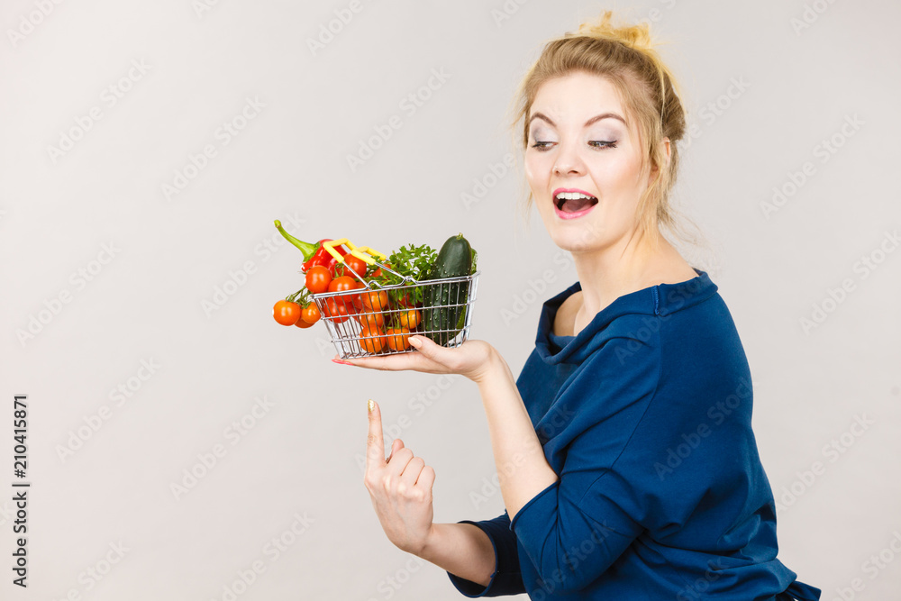Woman holds shopping basket with vegetables Woman holds shopping basket with vegetables