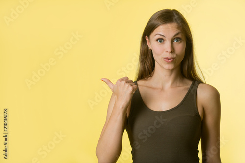 beautiful young girl with her hair on yellow background with a surprised look