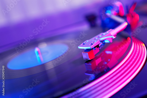 Turntable vinyl record player. Sound technology for DJ to mix & play music. Vintage vinyl record player on a background decorations for a party, bright disco lights. Needle on a vinyl record          