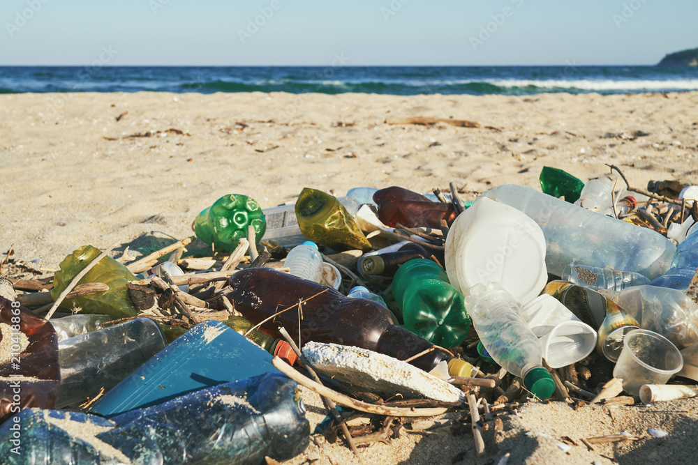 Spilled garbage on the beach of the big city. Empty used dirty plastic bottles. Dirty sea sandy shore the Black Sea. Environmental pollution. Ecological problem. Bokeh moving waves in the background Spilled garbage on the beach of the big city. Empty used dirty plastic bottles. Dirty sea sandy shore the Black Sea. Environmental pollution. Ecological problem. Bokeh moving waves in the background