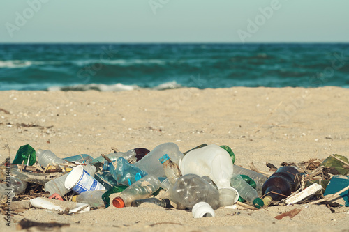 Spilled garbage on the beach of the big city. Empty used dirty plastic bottles. Dirty sea sandy shore the Black Sea. Environmental pollution. Ecological problem. Bokeh moving waves in the background   © marina_larina
