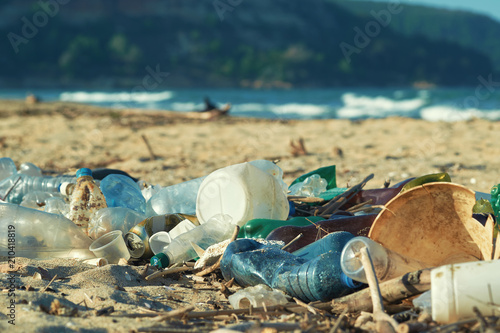Spilled garbage on the beach of the big city. Empty used dirty plastic bottles. Dirty sea sandy shore the Black Sea. Environmental pollution. Ecological problem. Bokeh moving waves in the background   © marina_larina