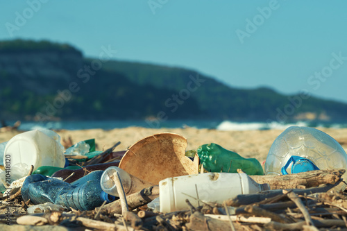 Spilled garbage on the beach of the big city. Empty used dirty plastic bottles. Dirty sea sandy shore the Black Sea. Environmental pollution. Ecological problem. Bokeh moving waves in the background   © marina_larina