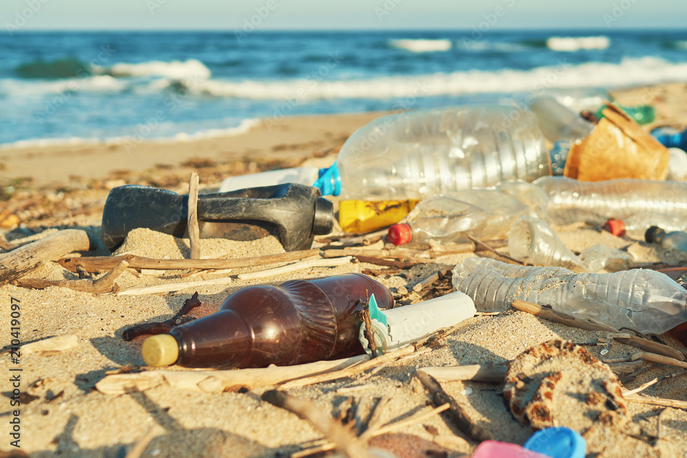 Spilled garbage on the beach of the big city. Empty used dirty plastic ...