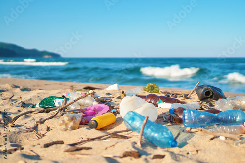 Spilled garbage on the beach of the big city. Empty used dirty plastic bottles. Dirty sea sandy shore the Black Sea. Environmental pollution. Ecological problem. Bokeh moving waves in the background  