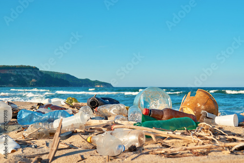 Spilled garbage on the beach of the big city. Empty used dirty plastic bottles. Dirty sea sandy shore the Black Sea. Environmental pollution. Ecological problem. Bokeh moving waves in the background   © marina_larina