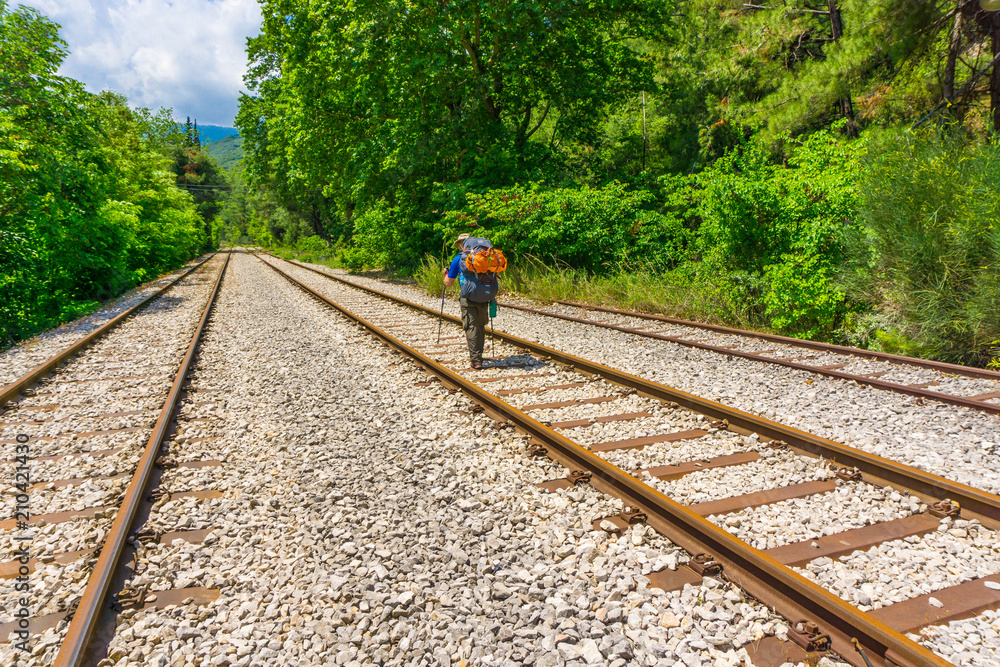 Fototapeta premium A hiker with his backpack is walking along an old railway near Asopos old railway station at national park of Oiti in Central Greece
