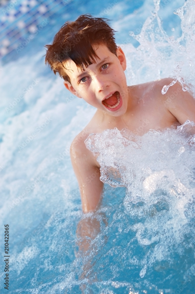 The young boy with great pleasure swims in the pool and shouts of joy. Vertical photo