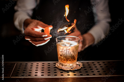 Barman making a fresh and tasty old fashioned cocktail with orange peel and smoke note