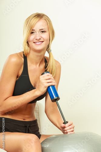 Fitness woman with air pump inflating fit ball