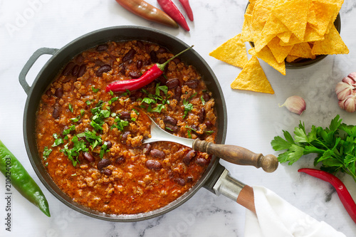 Mexican and American food Chili con carne served with nachos, pepper and herbs. photo