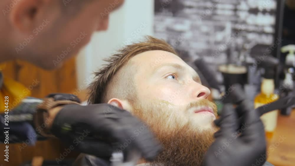 Hairdresser for men. Barbershop. Caring for the beard. Barber with hair clipper works on hairstyle for bearded guy barbershop background. Hipster lifestyle concept. Barber with clipper trimming hair Hairdresser for men. Barbershop. Caring for the beard. Barber with hair clipper works on hairstyle for bearded guy barbershop background. Hipster lifestyle concept. Barber with clipper trimming hair