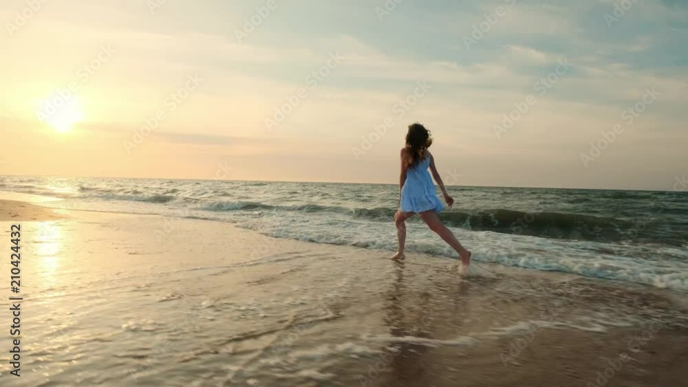 SLOW MOTION: Girl running in shallow water at sunset. A girl in a white dress is running at the water's edge near the sea. I am happy with the sea and the beach. Experiencing freedom SLOW MOTION: Girl running in shallow water at sunset. A girl in a white dress is running at the water's edge near the sea. I am happy with the sea and the beach. Experiencing freedom