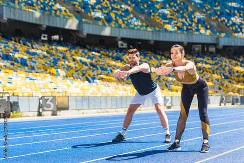 young sporty couple warming up before training on running track at sports stadium