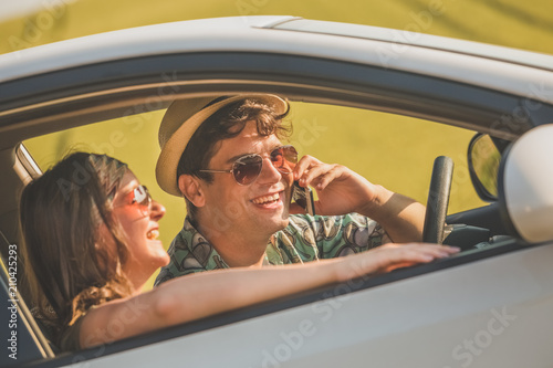 Fashionable couple sitting in car interior and using mobile phone. © zphoto83