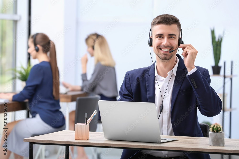 Male receptionist with headset at desk in office Male receptionist with headset at desk in office