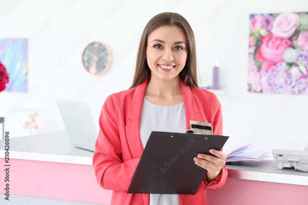 Beauty salon receptionist with clipboard near desk