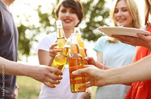 Young people with bottles of beer and food outdoors. Summer barbecue