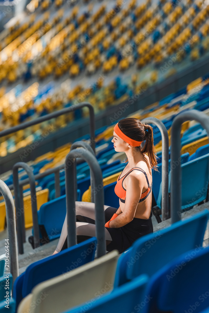 Fototapeta premium high angle view of beautiful young woman relaxing on stairs at sports stadium