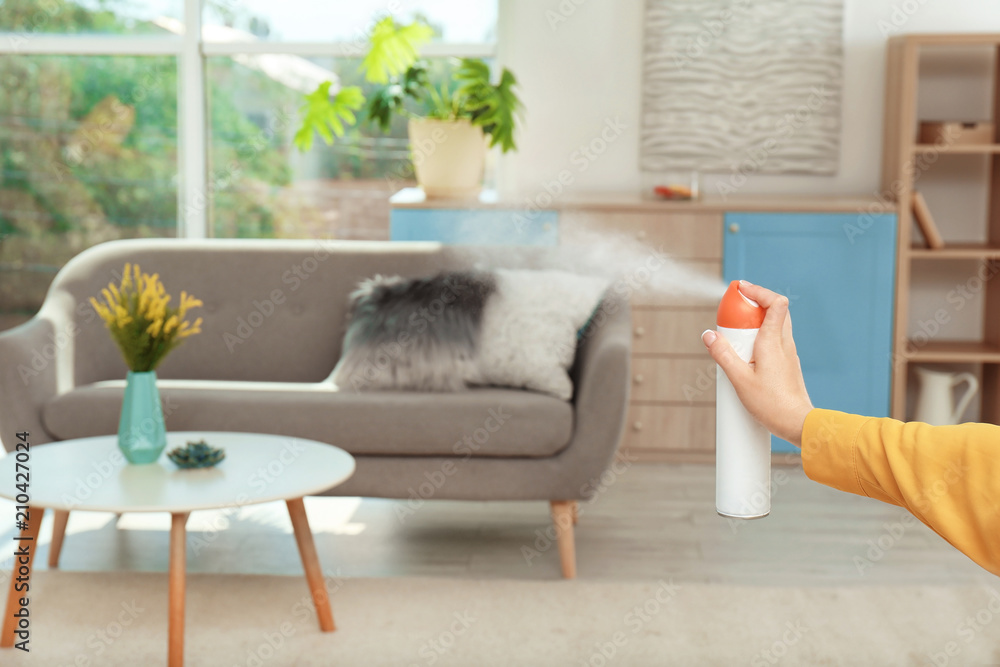 Woman spraying air freshener at home - obrazy, fototapety, plakaty 